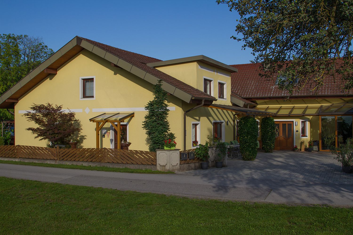 Yellow detached house with red roof and garden.