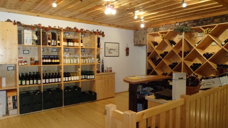 Interior view of a wine shop with wooden shelves full of wine bottles and spirits.