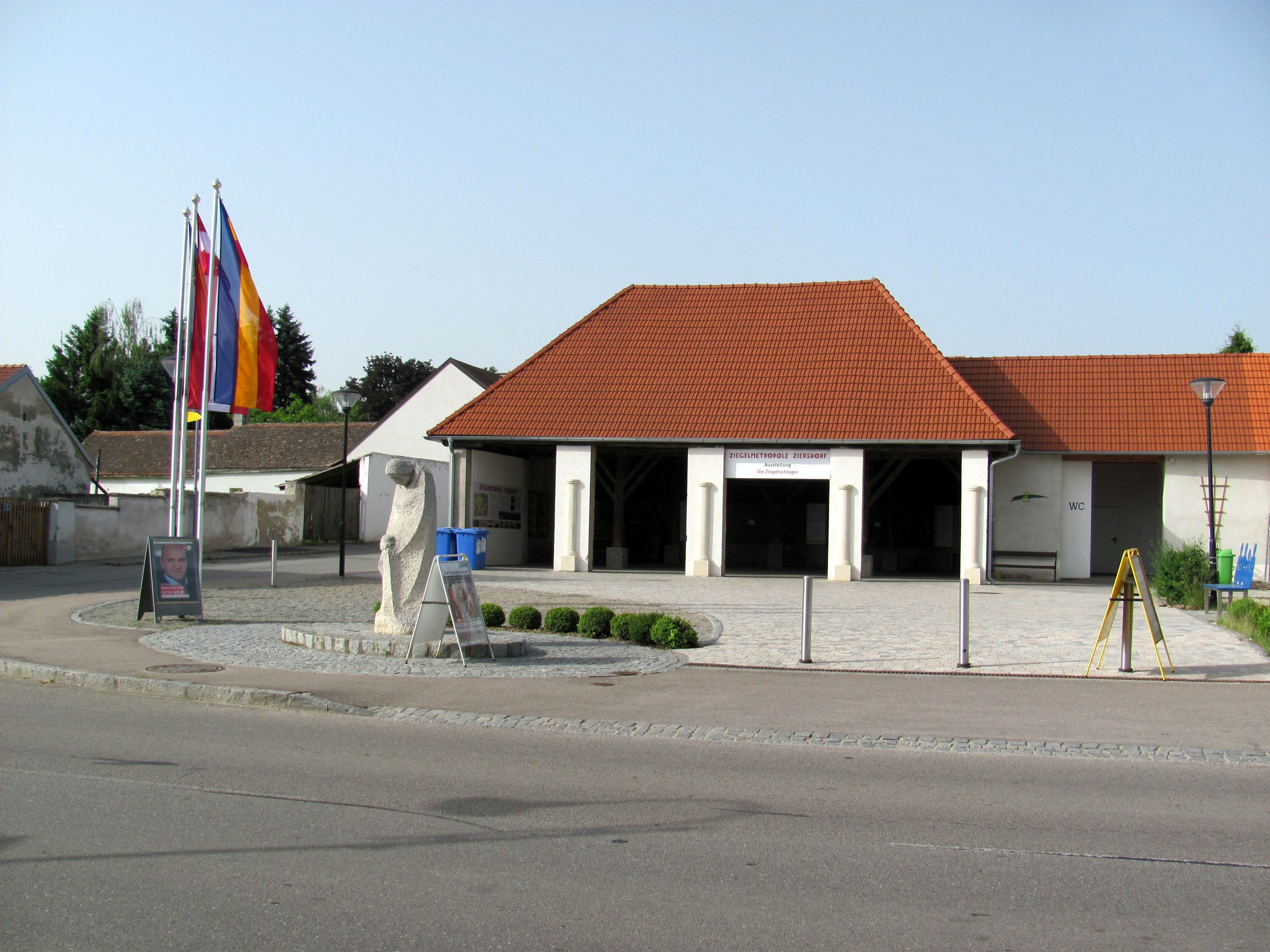 Exterior view of the brick museum in Ziersdorf with red roof tiles and flags.