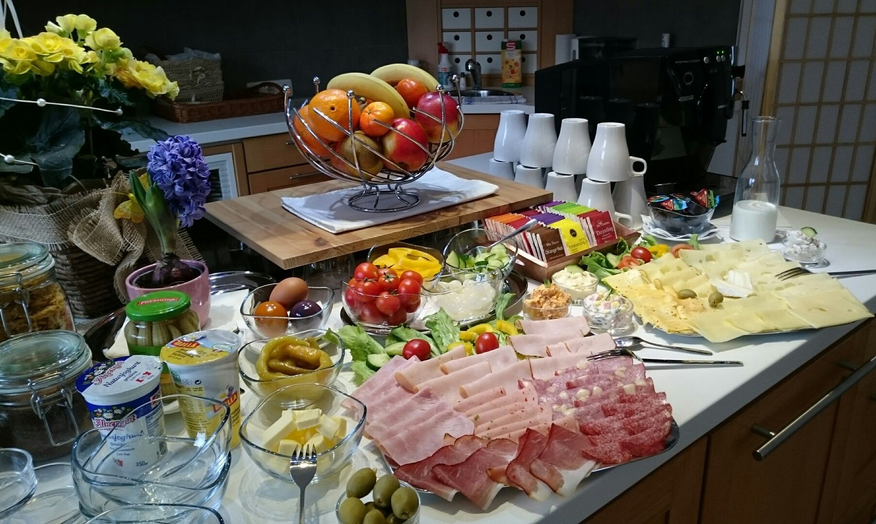 A rich breakfast buffet with cold cuts, cheese, fruit, vegetables and yogurt.