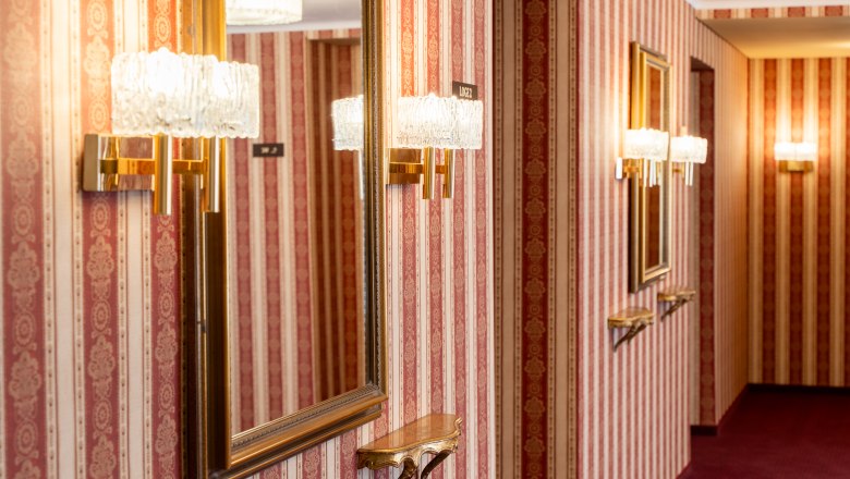 Nostalgic corridor in the Wiener Neustadt municipal theater with red and gold wallpaper, mirrors and crystal wall lights
