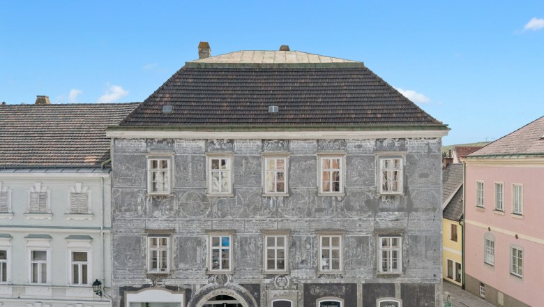 Historic building with a gray fa&ccedil;ade and decorative paintings in a town.