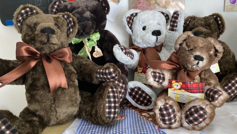 Five plush bears with bows sit on a table.