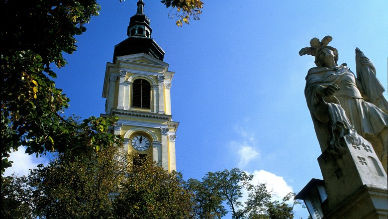 Tower of Großweikersdorf parish church with statue in the foreground.