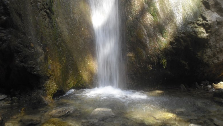 Waterfall in a rocky environment with a clear pool of water.