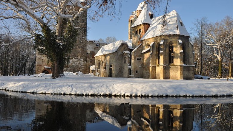 Pottendorf castle ruins in winter with snow and reflection in the water.