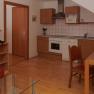 Compact kitchen with wooden cupboards, dining table and chairs, stove, sink and microwave.