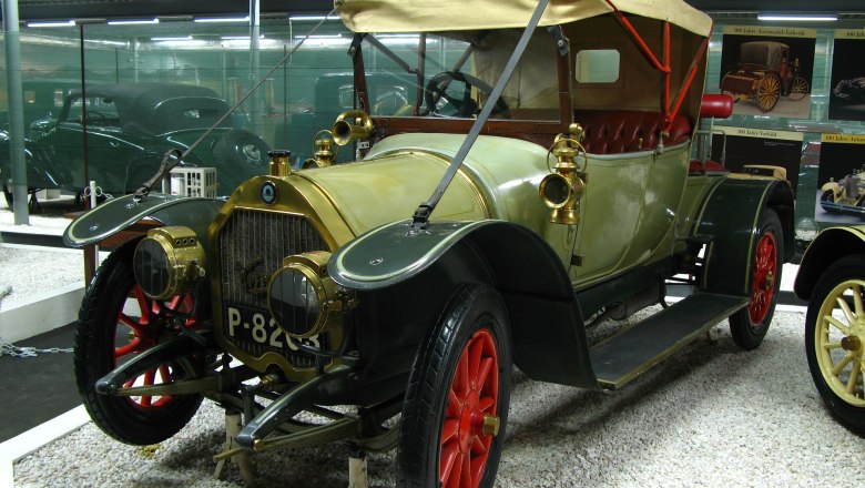 A vintage car with a red top and red wheels in an automobile museum.
