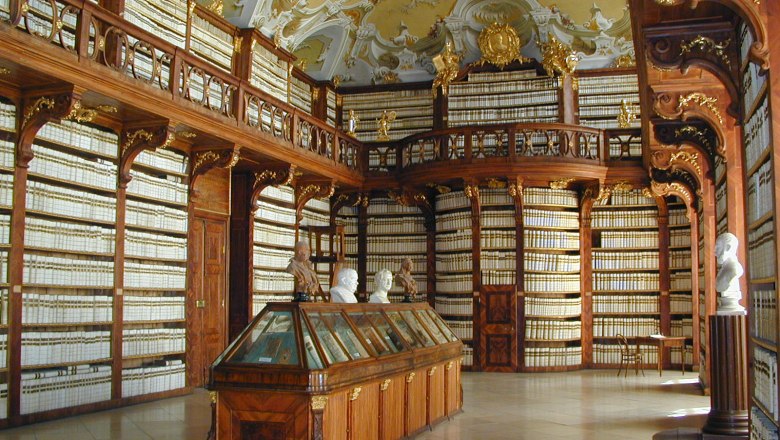 Interior view of the library in Seitenstetten Abbey with richly decorated wooden shelves and busts.