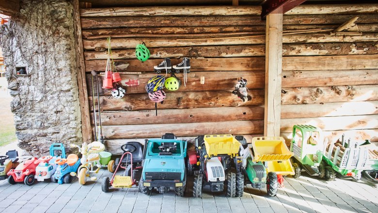 Toy vehicles and helmets in a woodshed.