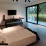 Modern bedroom with large window and view of a pond.