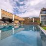 Exterior view of a modern hotel with pool and sun loungers.