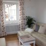Bright living room with beige sofa, cushions, coffee table and window with curtains.