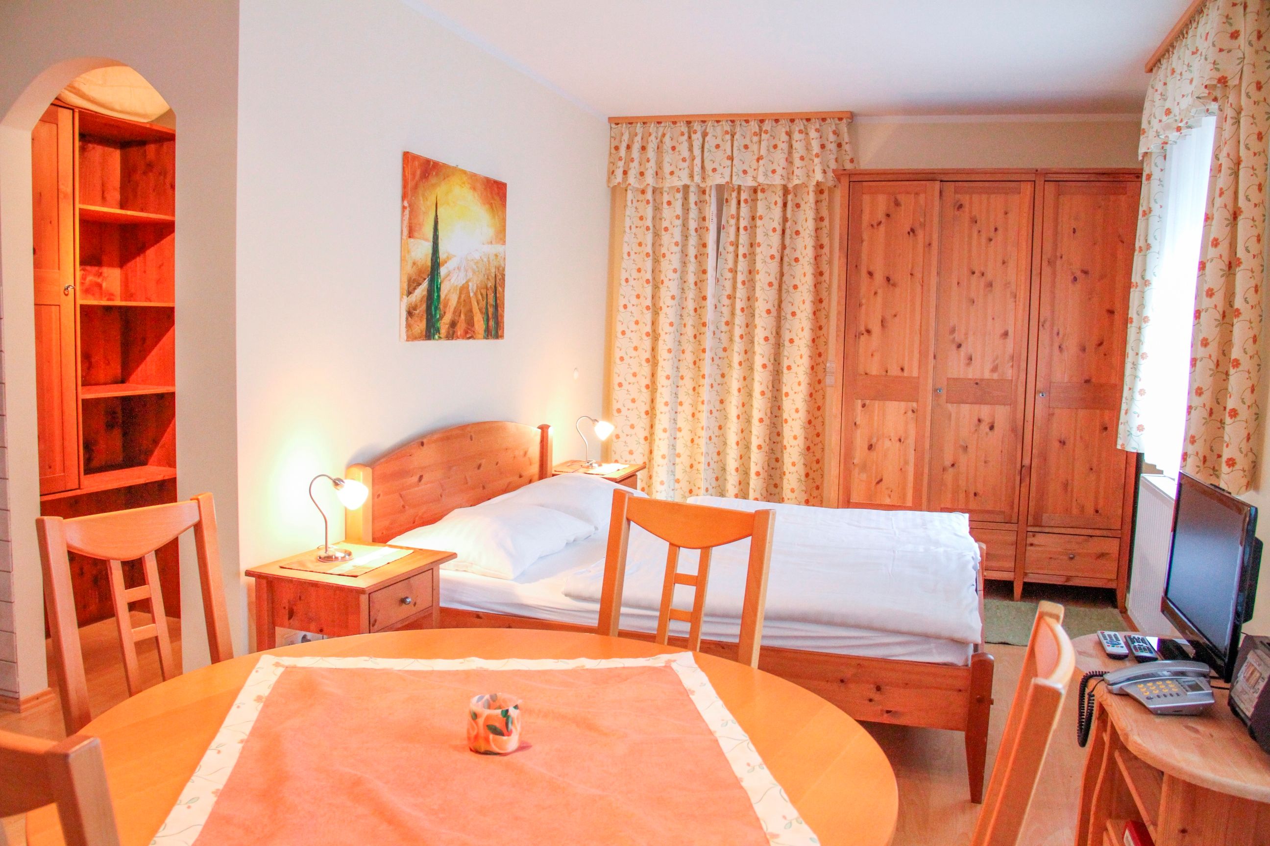 Small apartment with wooden furniture, bed, table and wardrobe.