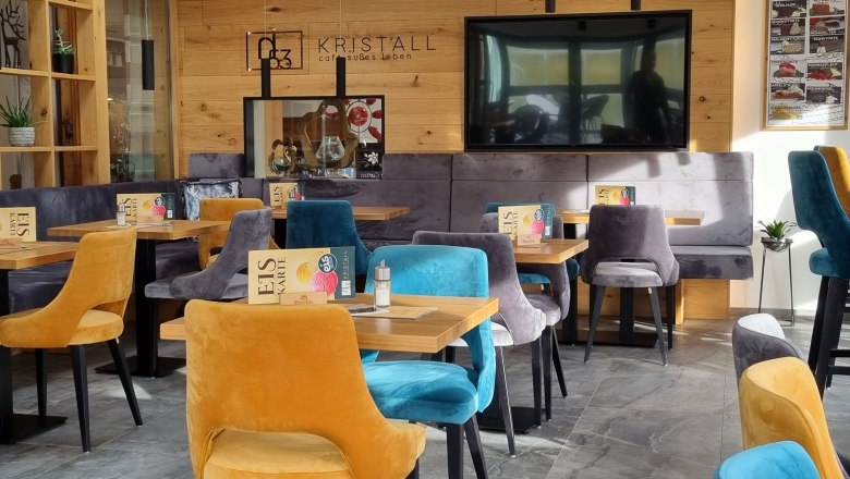 Interior view of a modern caf&eacute; with colorful velvet chairs and wooden walls.