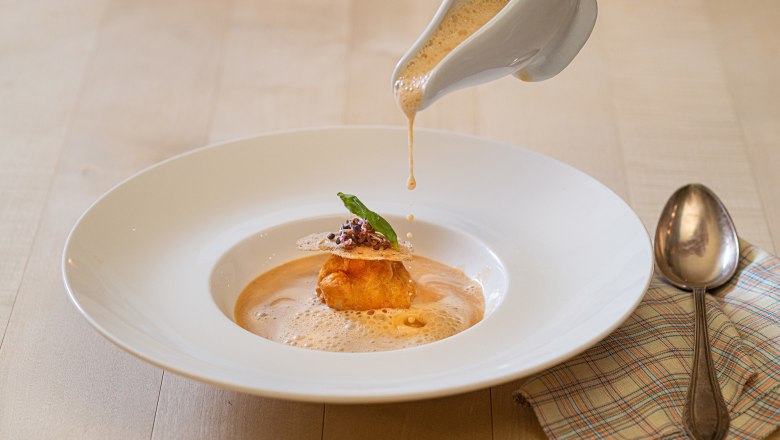 Crab soup is poured into a plate, decorated with a dough ball and herbs.