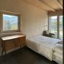 Bedroom with bed, wooden ceiling, window with mountain view and chest of drawers.