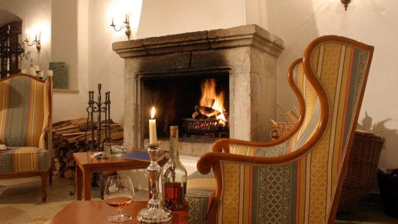 Cozy fireplace lounge with a burning fireplace, armchairs and table with drinks.