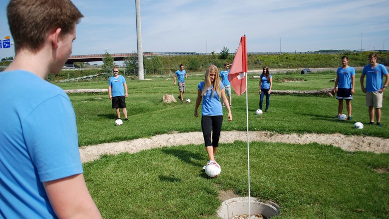 A group of young people playing soccer golf.