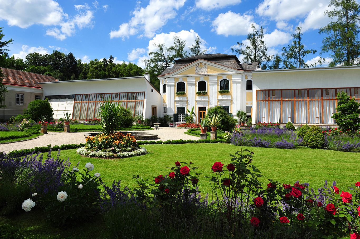 Orangery of Zwettl Abbey with well-tended garden and blooming flowers.