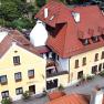 Aerial view of a yellow guest house with red roofs and flower boxes.