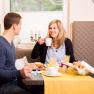 Two people having breakfast at a table with a yellow tablecloth.