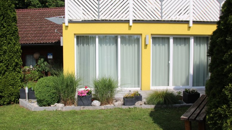 Yellow garden apartment with large windows and well-kept garden.