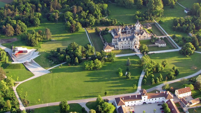 Aerial view of Grafenegg Castle with surrounding park and modern stage.