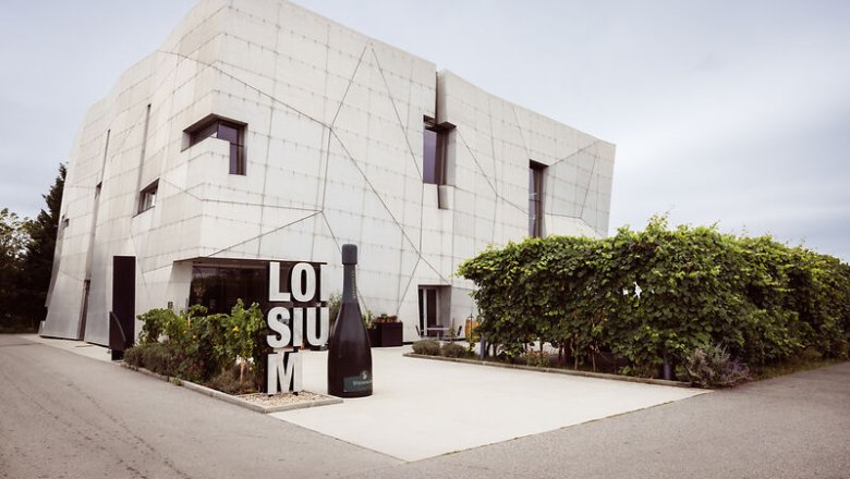 Modern building of the Loisium with wine bottle and vines in the foreground.