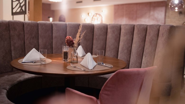 Elegant restaurant with round bench and table setting.