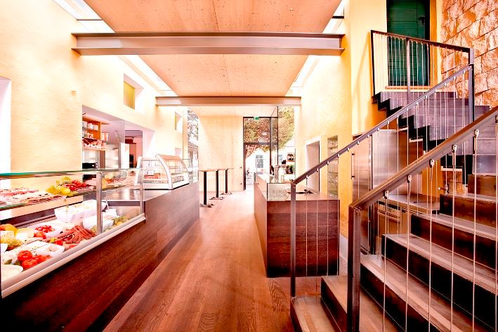 Interior view of a modern buffet with wooden floor, stairs and glass cabinets.