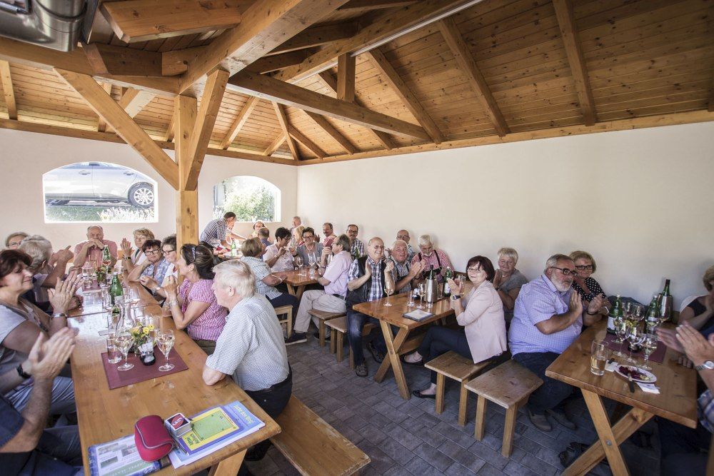 People sitting at wooden tables in a wine tavern and gossiping.
