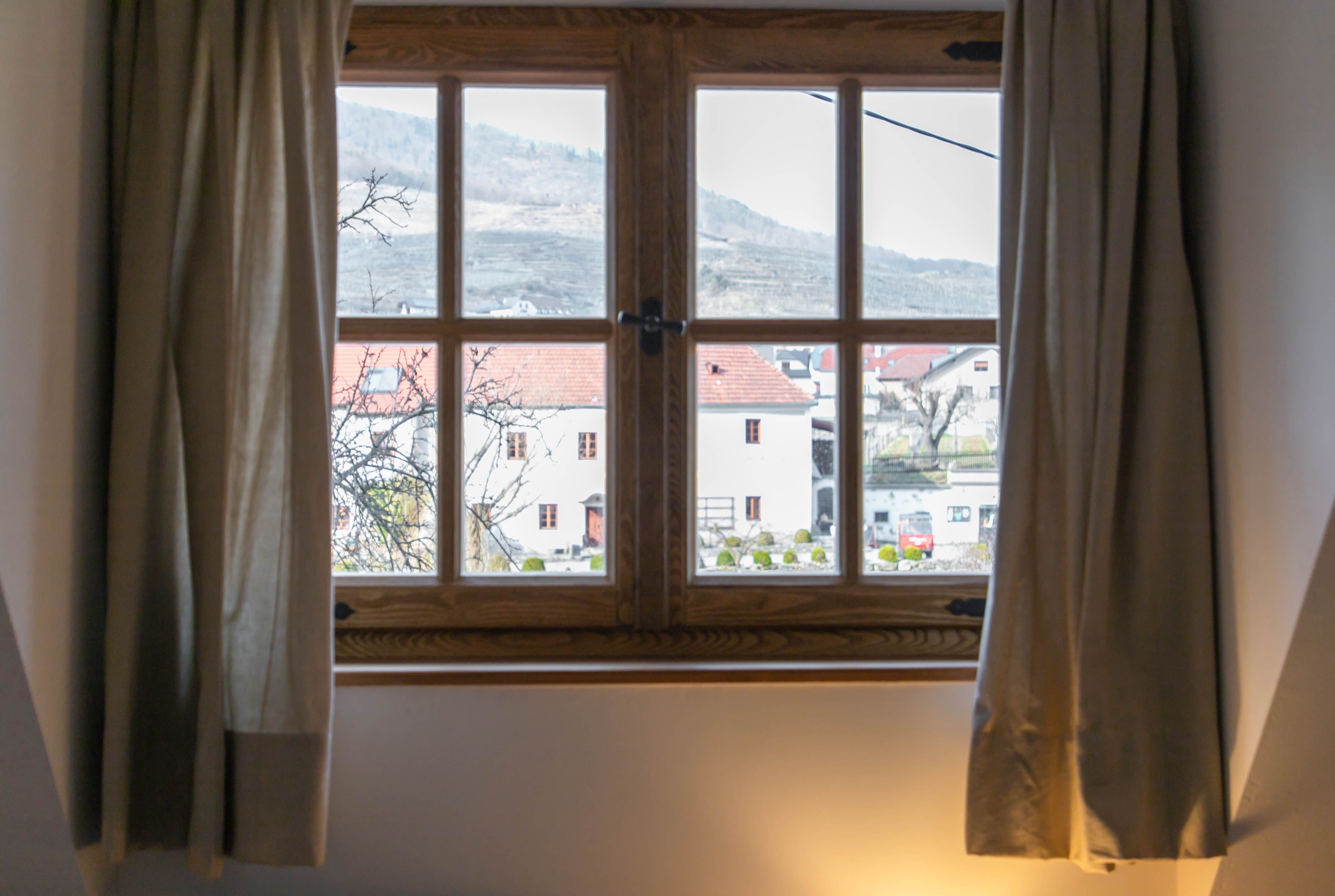 View from a window of a rural scene with houses and hills in the background.