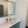 Modern bathroom with mirror, washbasin and soap dispenser.