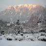 Snow-covered landscape with mountains in the background, illuminated by the evening sun.