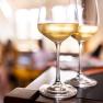 Two wine glasses with white wine on a table, blurred background.