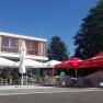 A modern guest garden with parasols and seating in front of a building in sunny weather.