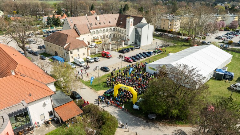 Aerial view of a castle with a crowd of people, tents and buildings during the Rosalia Trail Challenge.
