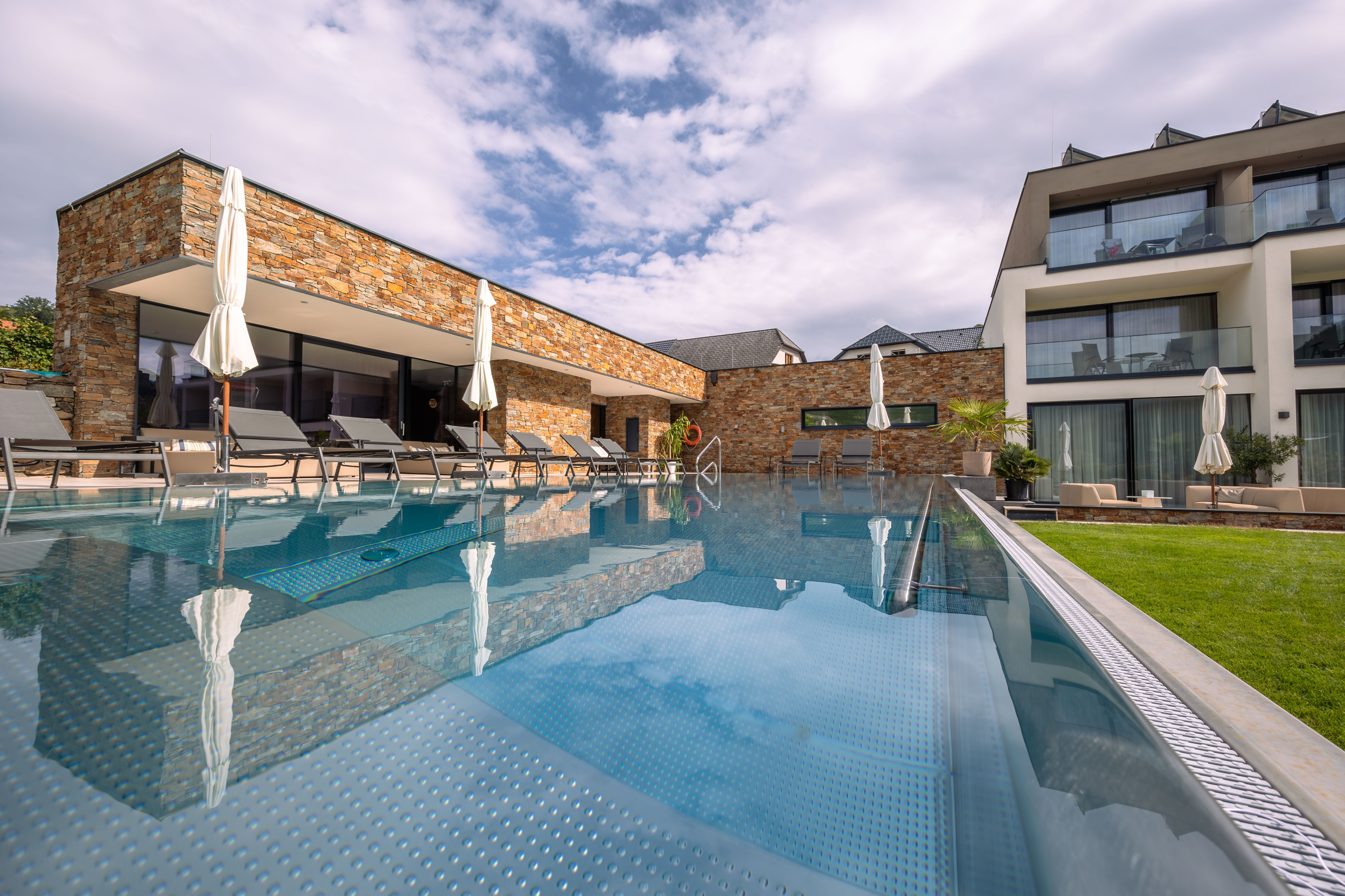Exterior view of a modern hotel with pool and sun loungers.