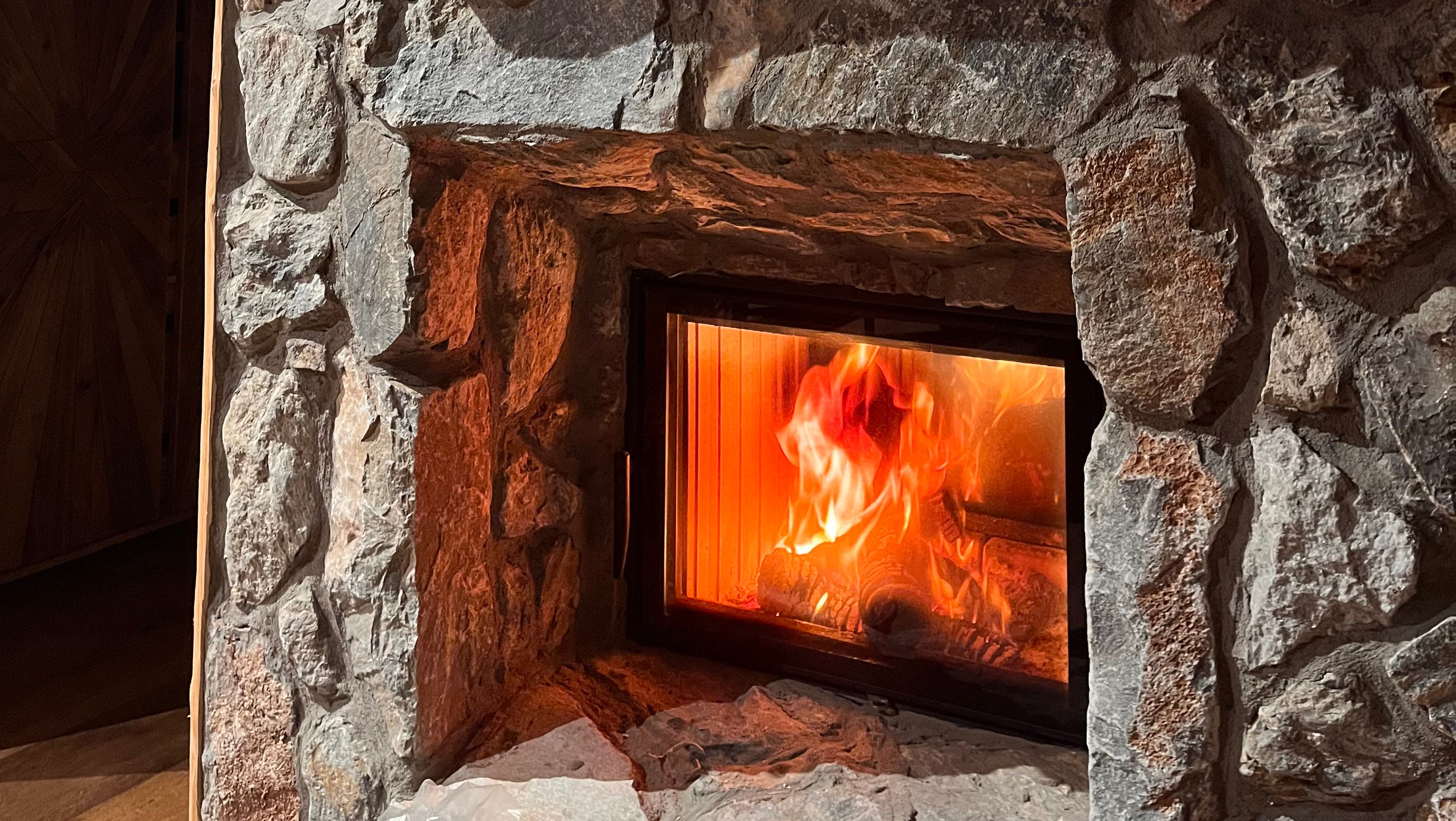 A burning fireplace built into a stone wall.