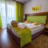 Room with double bed, wooden floor and green curtains