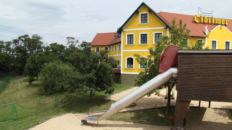 House, © Oldtimer Yellow building with red roof and slide in the foreground.