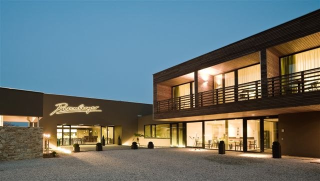 Modern building of the Rosenberger winery at dusk with illuminated lettering.