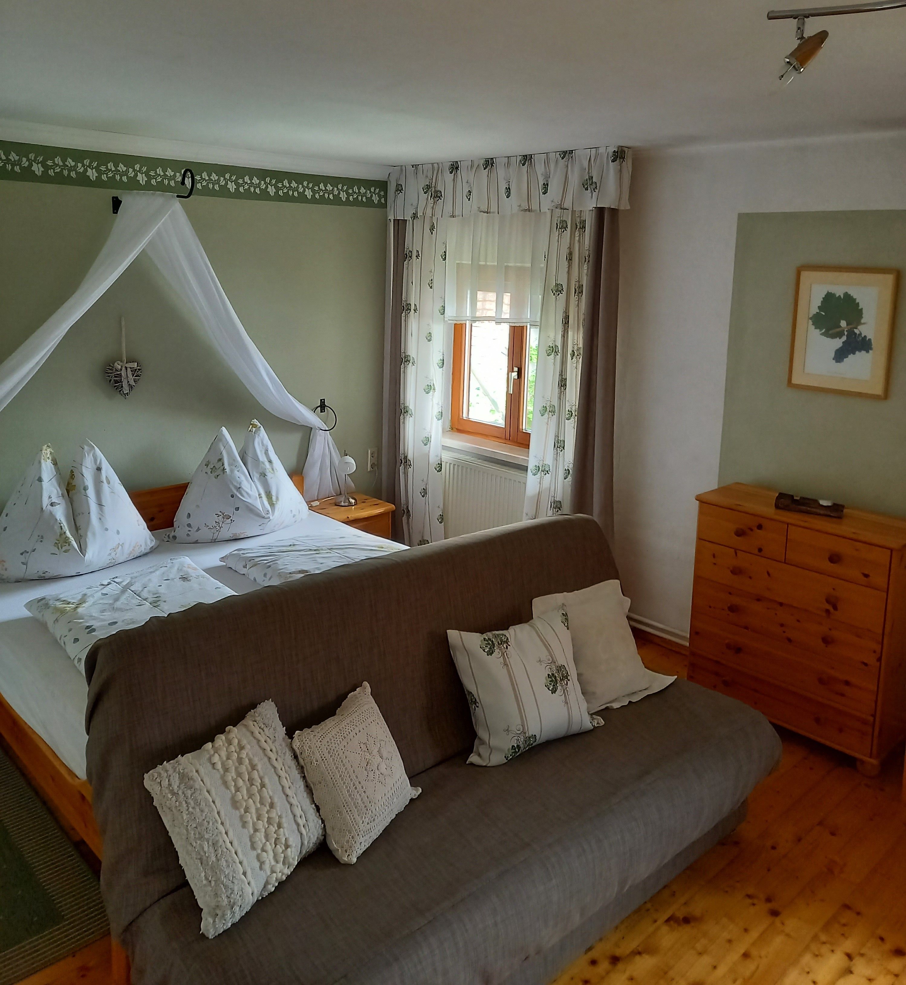 Cozy guest room with double bed, sofa and wooden furniture.