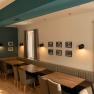 Interior view of a restaurant with wooden tables, upholstered benches and chairs, decorated with pictures on the walls.