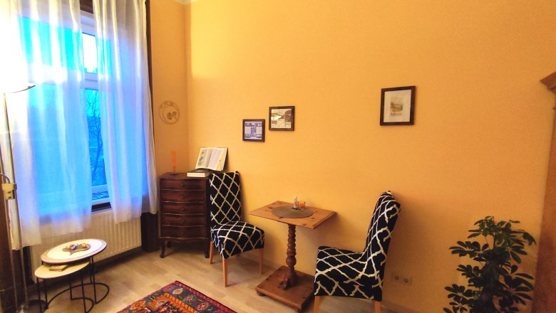 Cozy room with two chairs, small table, carpet and plants.