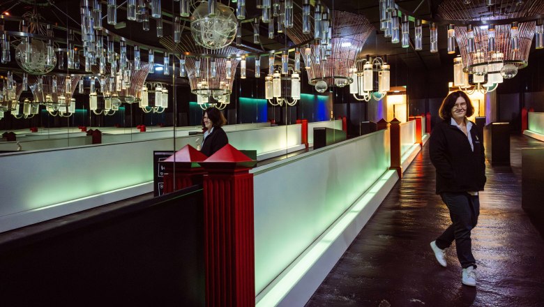 A person walks through a room with futuristic lighting and mirrors.