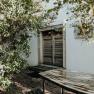 Wooden door behind trees with table in the foreground.