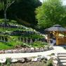 A well-tended garden with a wedding pavilion surrounded by chairs and greenery.
