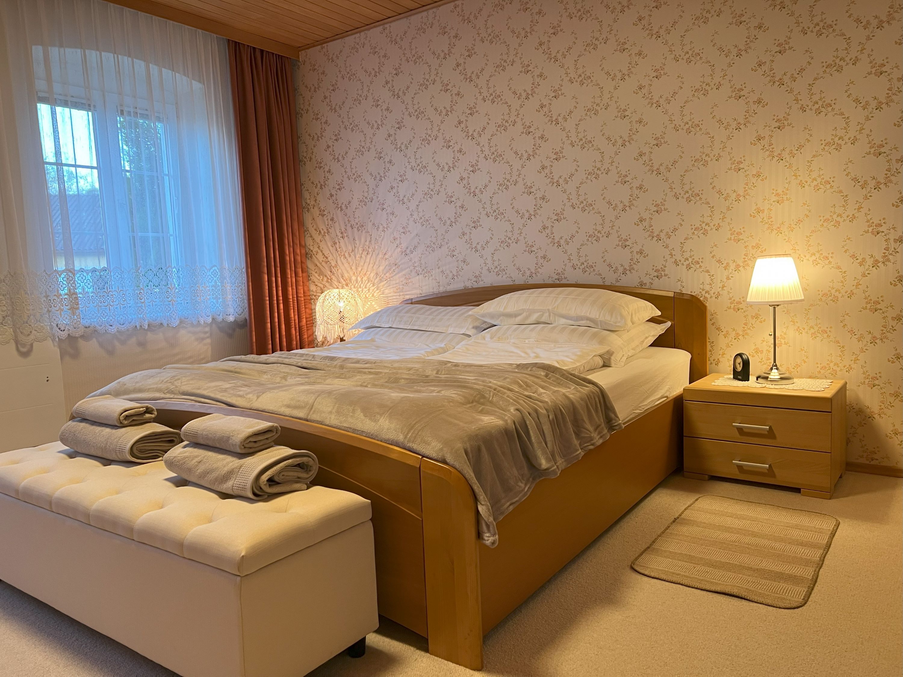 Cozy bedroom with double bed, bedside lamp and window with curtains.